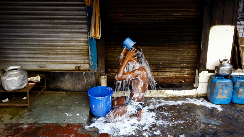 Man taking a bucket shower in India